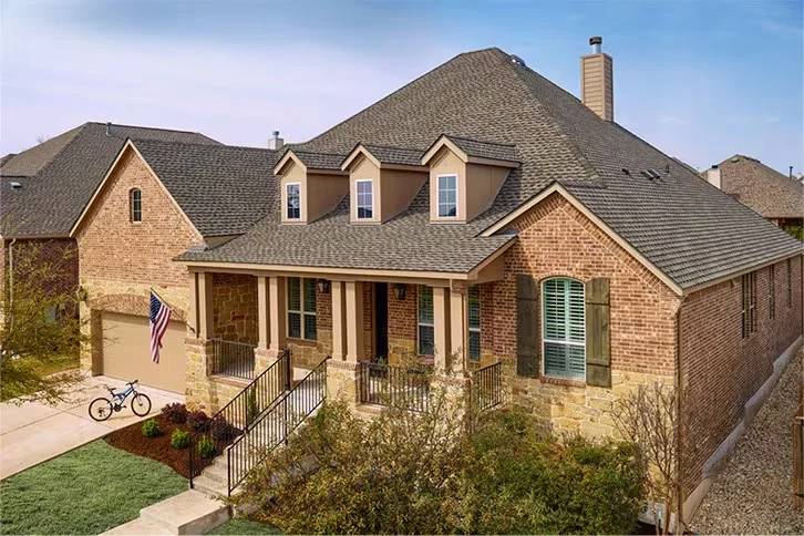 GAF Timberline UHDZ shingles in Weathered Wood on a brick and stone home with dormers, showing the Dual Shadow Line, from GAF's official Timberline product page